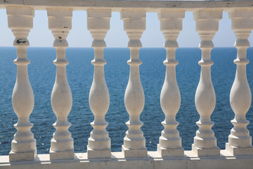 Baluster beach. White columns overlooking the sea. View of white pillars and horizont on blue sea and the sky in the background