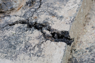 Cracked asphalt on the road for vehicles. Damaged road surface.
