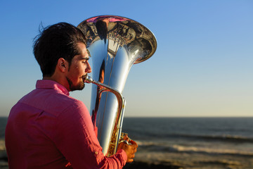 Musician playing the Tuba on the ocean coast.