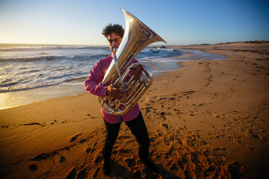 Musician playing the Tuba on the ocean coast.