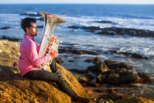 Musician playing the Tuba on the ocean coast.