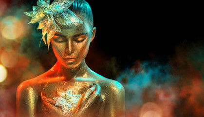 Mannequinvrouw in kleurrijke heldere gouden fonkelingen en neonlichten die met fantasiebloem stellen. Portret van mooi meisje met gloeiende make-up