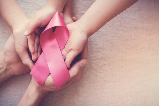 hands holding pink ribbon, breast cancer awareness, October pink concept