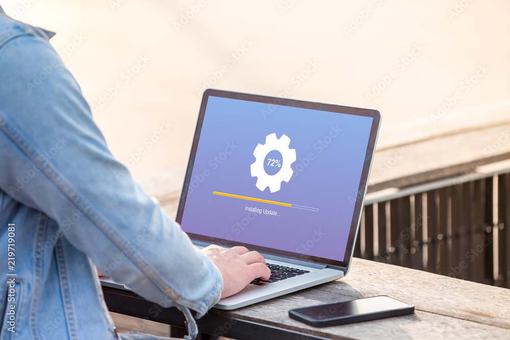 Poster a man is working using laptop doing installing update process with gearbox percentage at outdoor