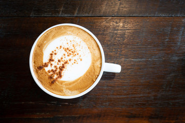 Cup of cappuccino coffee on wooden table in the coffee shop, top view