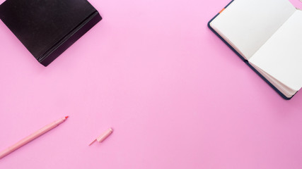 notebook and pen on pink background.Top view