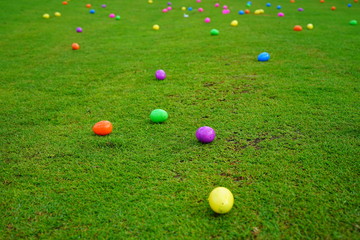 An Easter egg hunt with colorful plastic eggs on a green lawn