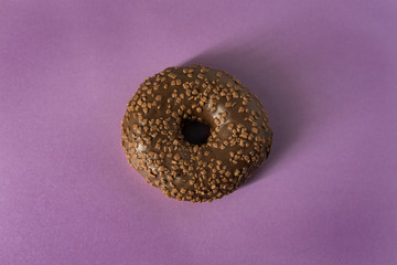 Single glazed chocolate donut on purple block colour background - minimalism, copy space