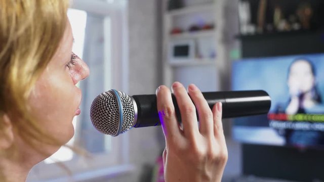 Close up. a woman screaming to a microphone. a woman sings karaoke into a microphone in a home setting. 4k, slow motion