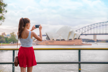 Naklejka premium Kobieta turysta w Sydney podróżując telefonem z Opery na wakacjach w Australii. Azjatyckie dziewczyny za pomocą telefonu komórkowego do zdjęć podczas wakacji.