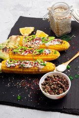 Grilled corn with cream sauce, spices, jalapeno on the black stone tile.