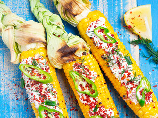 Grilled corn with cream sauce, spices, jalapeno on the blue boards