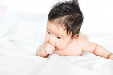 Asian baby girl with hand in mouth