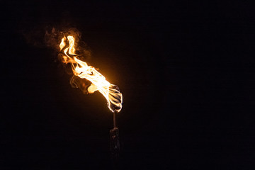 Burning Torch in the Night at black background - obrazy, fototapety, plakaty
