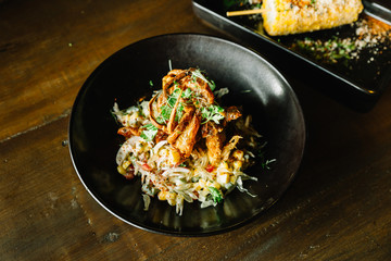 Mexican style pomelo salad topping with deep fried soft shell crab in black plate.