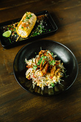 Mexican style pomelo salad topping with deep fried soft shell crab in black plate. With grilled corn.