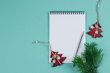 Fototapeta premium Christmas mock up blank greeting card. Fir tree branches and holday decorations over green paper background. Flat lay. Top view. Copy space