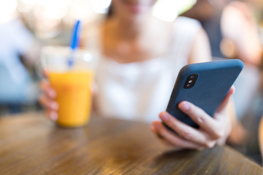 Woman enjoy iced drink and use of mobile phone inside coffee shop