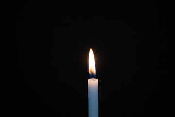 One light candle burning brightly on black background