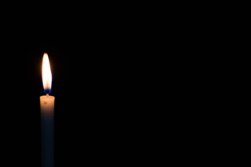 One light candle burning brightly on black background