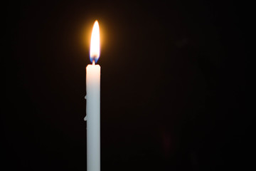 One light candle burning brightly on black background