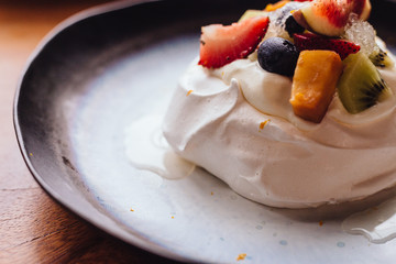 Meringue topping with fresh fruits including strawberry, mango, kiwi, blueberry and common fig served with sour fruit sauce.