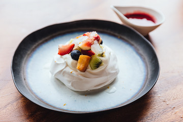 Meringue topping with fresh fruits including strawberry, mango, kiwi, blueberry and common fig served with sour fruit sauce.