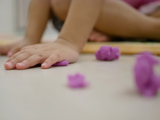 Obraz na płótnie Canvas Selective focus of little baby's hands playing play dough on the floor at home