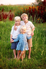 Three Precious Little Blonde Children Holding Hands Outside in the Garden