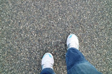 White sneakers and blue jeans on colorful gravel on the floor in the park. Background concept. Soft focus.