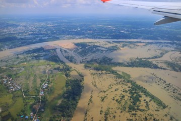 Naklejka na ściany i meble Aerial view of flood area in northeastern of thailand, view from airplane window with airplane's wing in the morning. Soft focus. Nature and transportation concept.