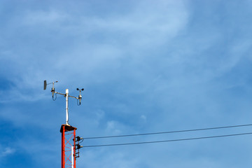 Poles equipped with marine weather monitoring equipment with sky background.