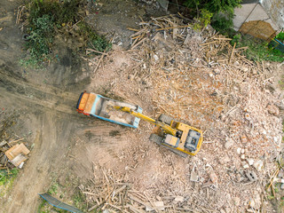 excavator working on demolition site and loading debris into dumper truck. aerial view 