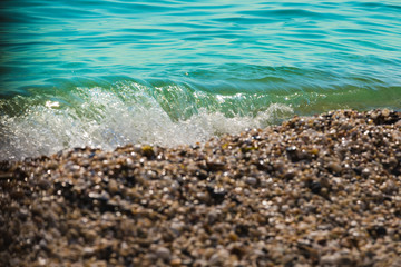 Fototapeta na wymiar Waves of the blue sea crashing onto a pebble beach in Maronia, Rodopi, Greece