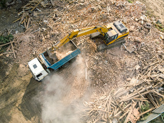crawler excavator loading debris of a destroyed building in truck. aerial view of demolition site