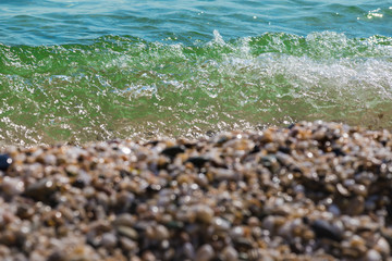 Waves of the blue sea crashing onto a pebble beach in Maronia, Rodopi, Greece