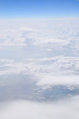Airplane flying in the blue sky among clouds and sunlight
