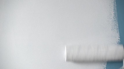 Roller painting blue wall with white paint - Powered by Adobe