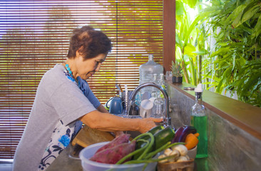 senior happy and sweet Asian Japanese retired, woman cooking at home kitchen alone neat and tidy washing the dishes smiling cheerful in house chores