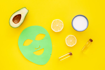 Skin care. Facial mask, cream and lotion near avocado and lemon on yellow background top view