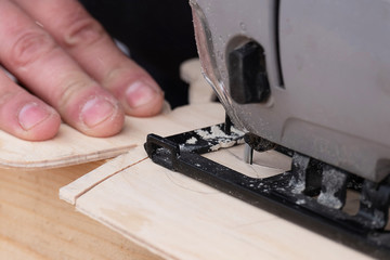 grey electric jigsaw to cut the plywood half-circle, wood background
