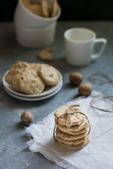 Oatmeal cookies tied with a rope on a white linen napkin and cookies on a plate in the background