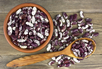 Haricot beans in bowl on wooden background  with wooden spoon