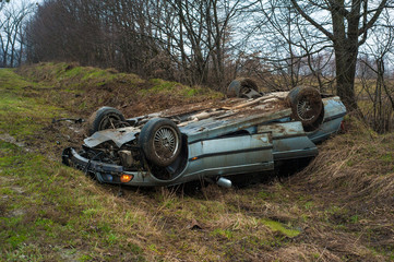The car got into an accident on the highway. The blue car turned over in a ditch near the highway.