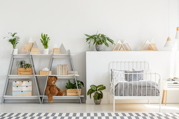 A classic child bedroom interior with simple, scandinavian style furniture and a gray wooden bookcase with a teddy bear