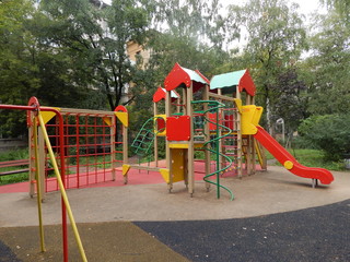 An empty children's playground with swings, carousels and a sandbox in the yard