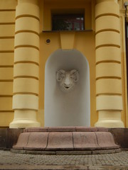 Sculpture of the ram's head on the wall of the yellow and white building as an architectural decoration