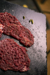Raw pork chop with spices on a dark background.