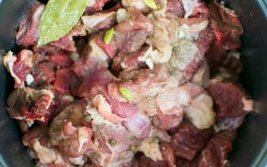 Raw pork chop with spices in a dark saucepan.