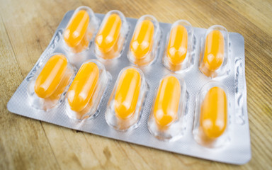 Yellow pills in a blister on a wooden background.